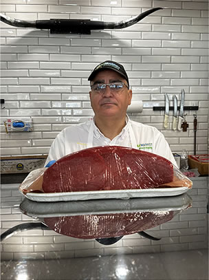Brazmarket butcher showing a large cut of beef at the meat counter