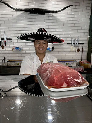 Brazmarket butcher presenting a fresh cut of beef at the counter