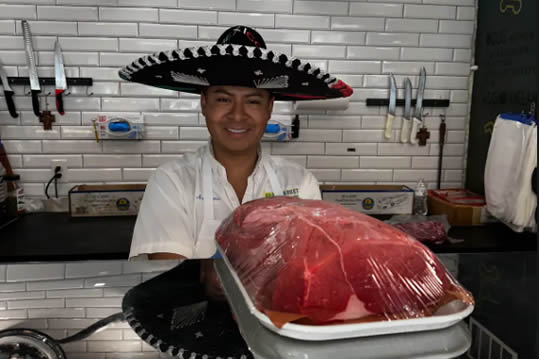 Butcher holding a fresh cut of beef at Brazmarket in Fort Myers